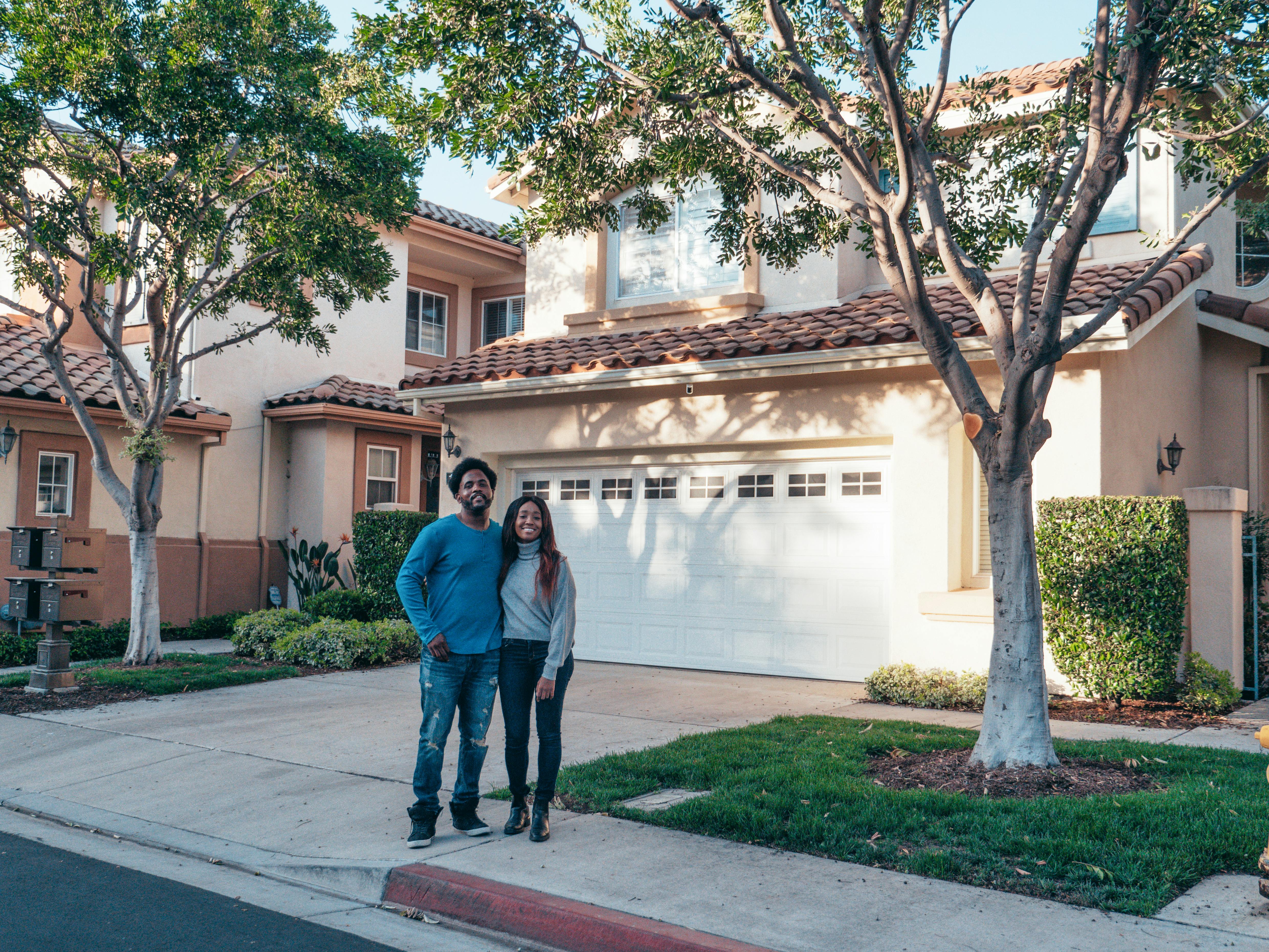 Couple posing in front of new house