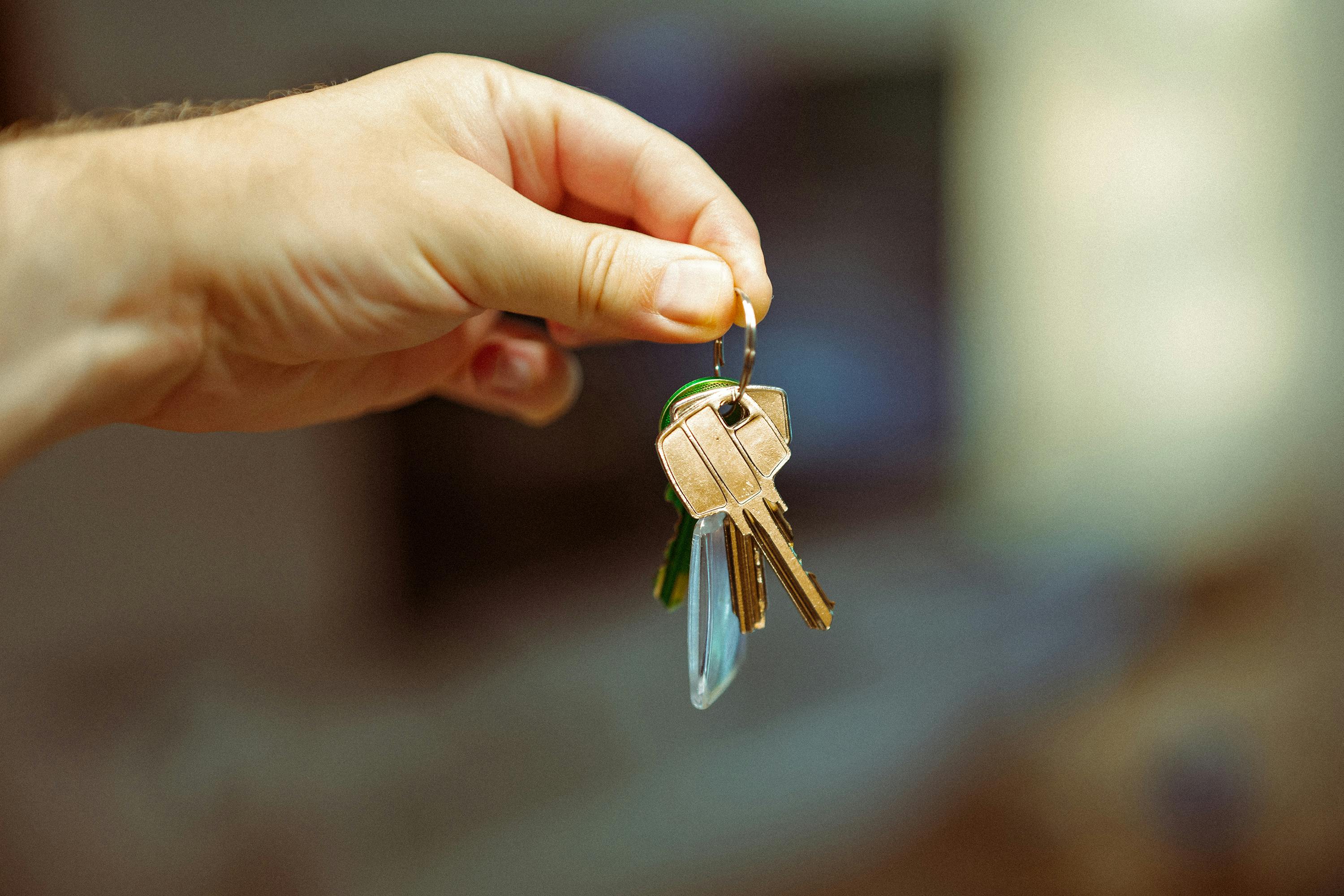 A close-up image of a hand holding a keyring with several house keys