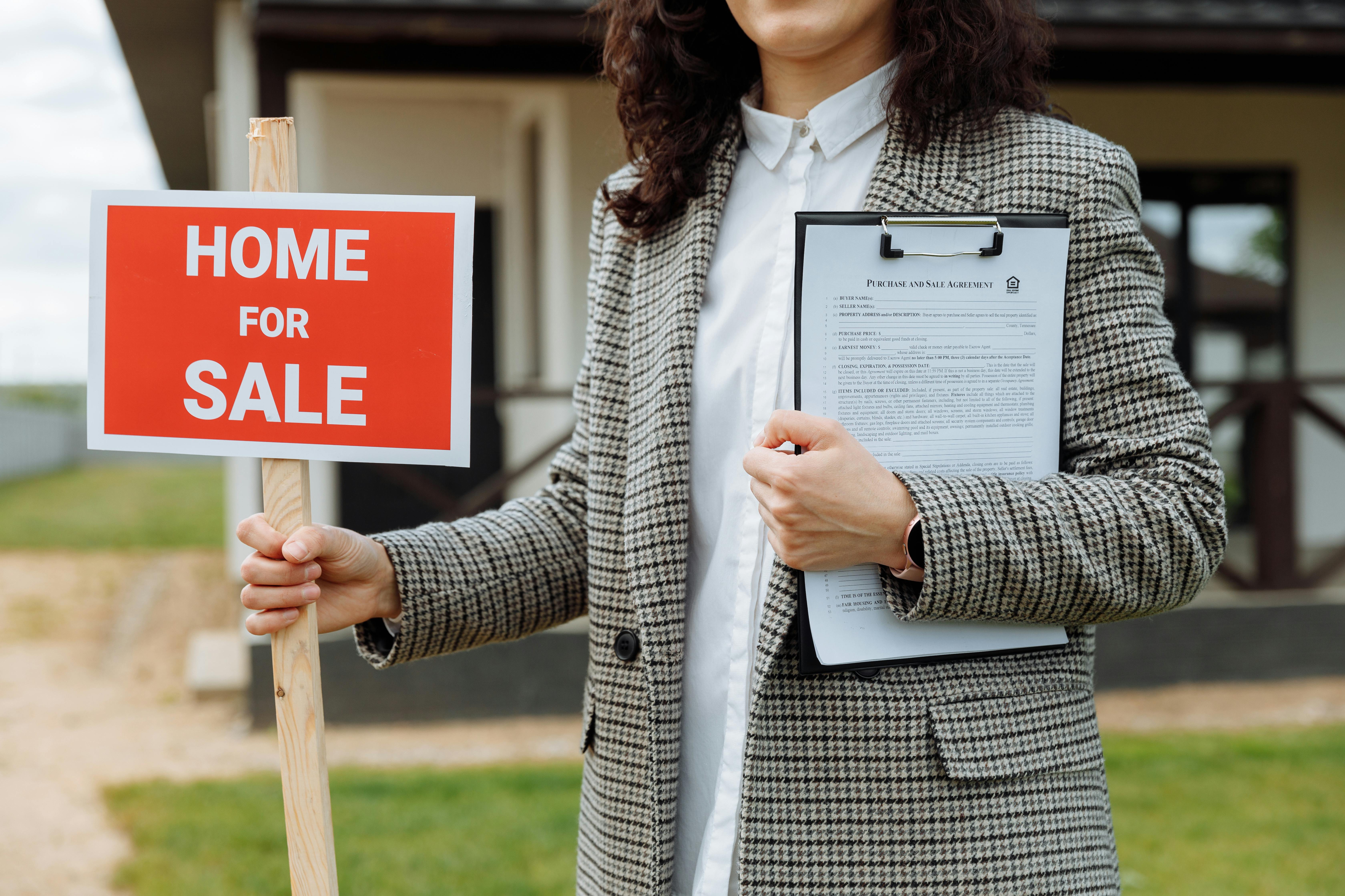 Real estate agent with a home for sale sign