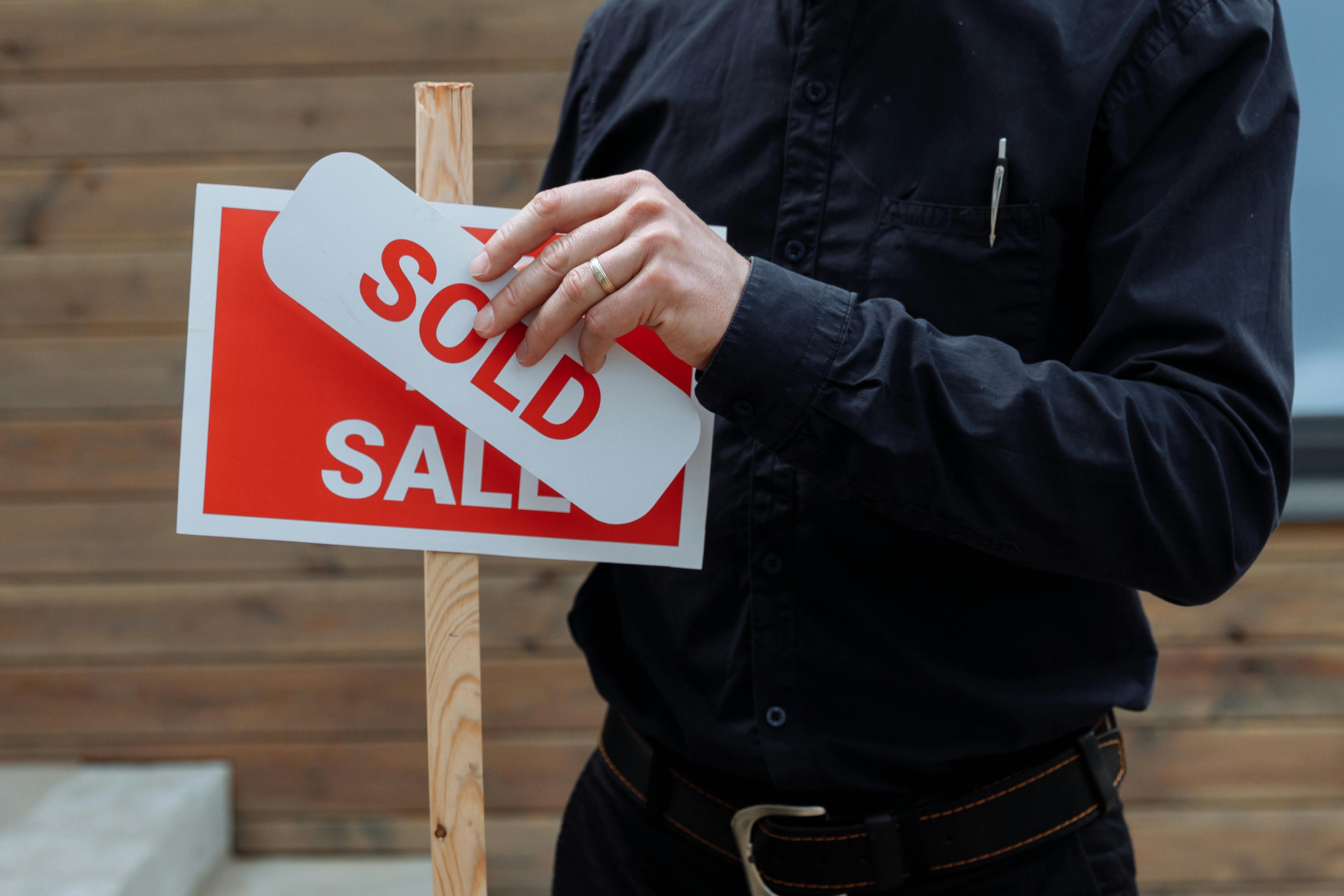 Real estate agent placing a sold sticker