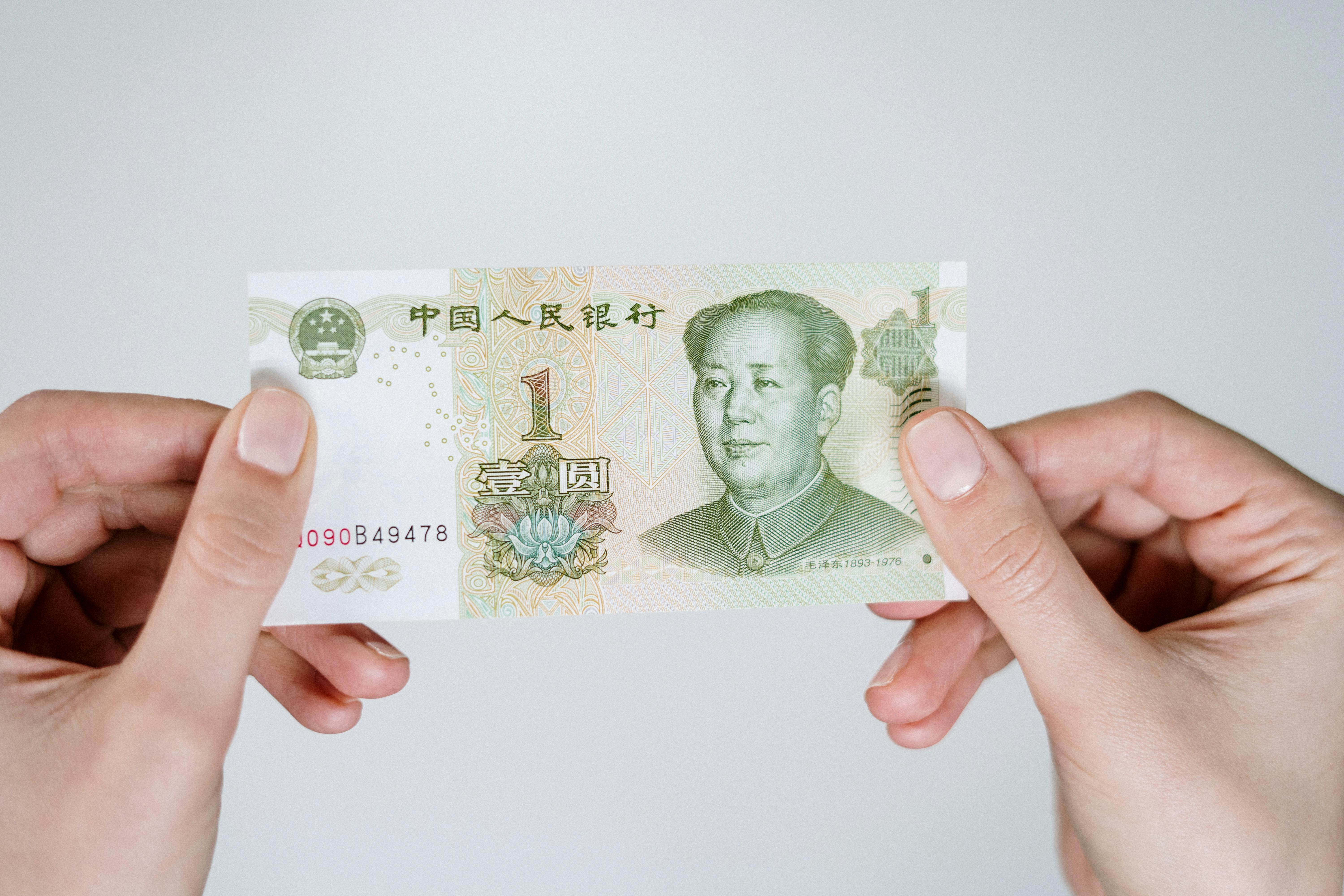 Hands holding a Chinese Yuan note