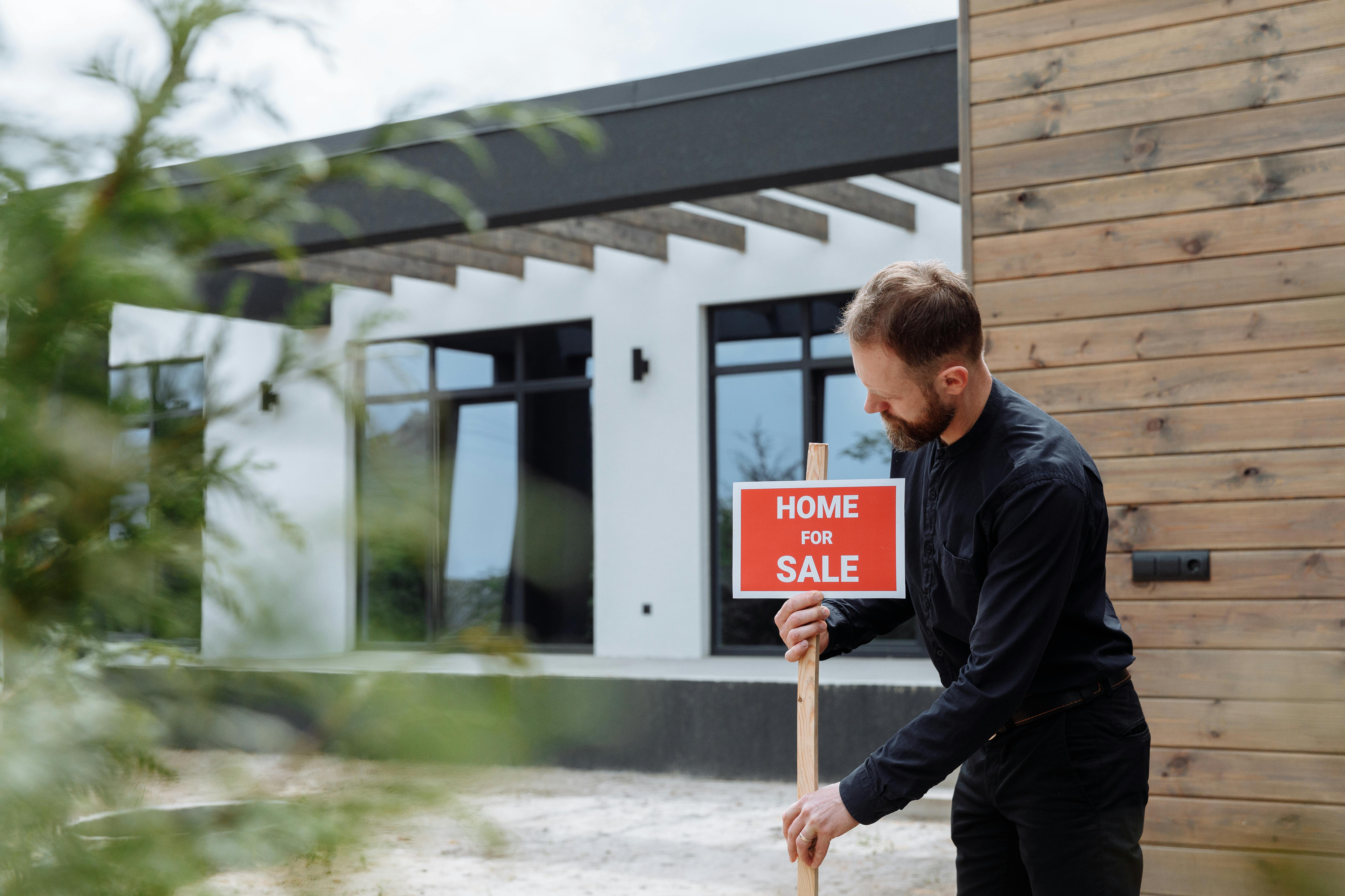 Man placing a home for sale sign