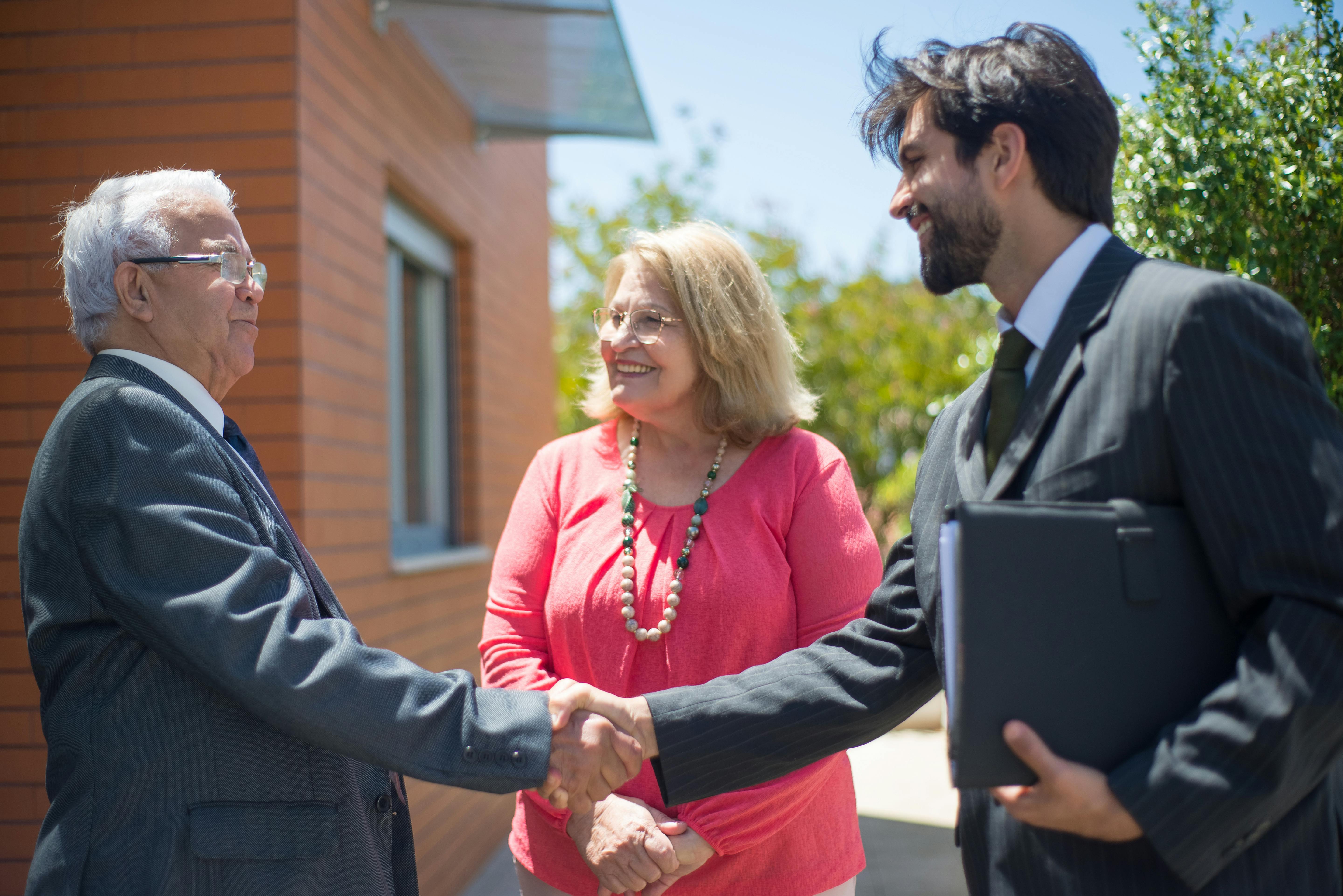 Real estate agent and mature couple shaking hands