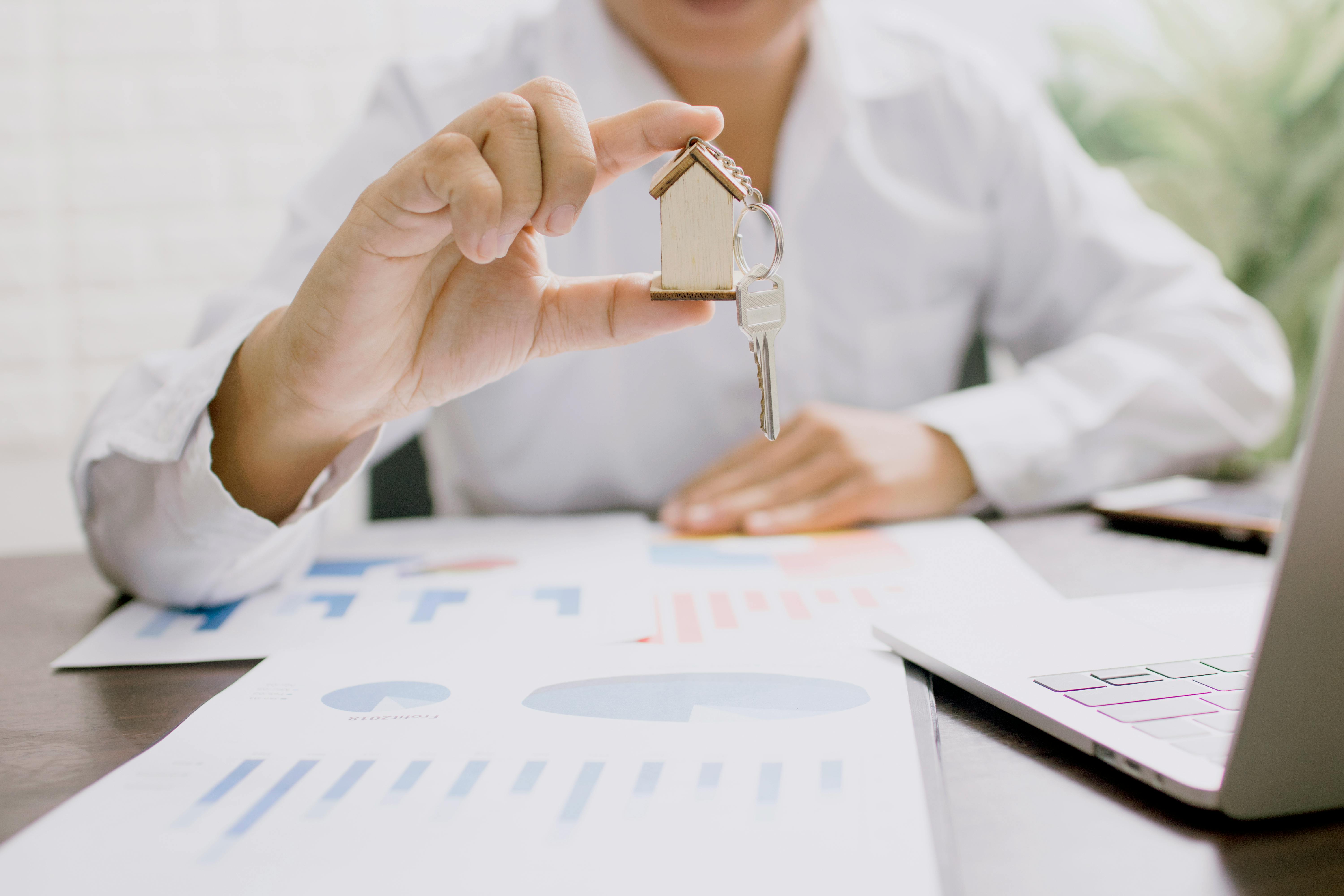 Real estate professional presenting a house model with keys